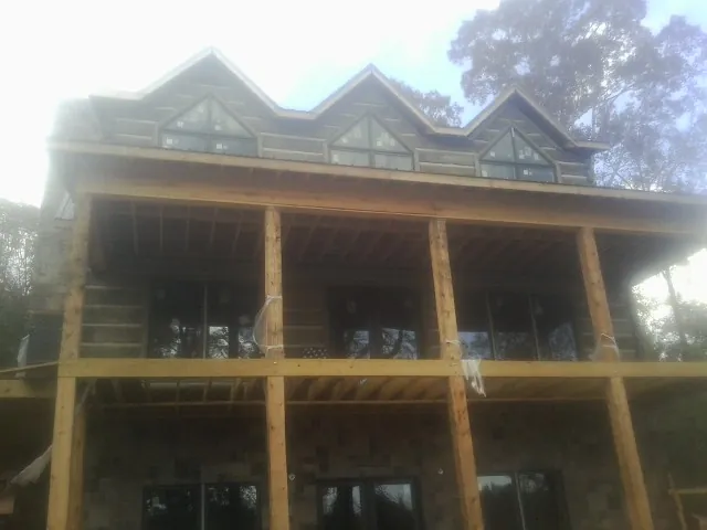 Dormers and porch framing on a large log home under construction — Roof Coating work by our crew in Elberta