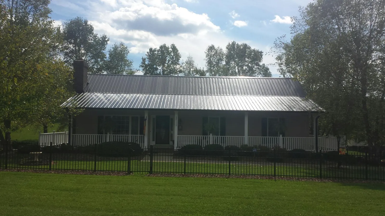 Gray metal roof on a brick ranch with a full width front porch — Gutter Guard Installation work by our crew in Elberta